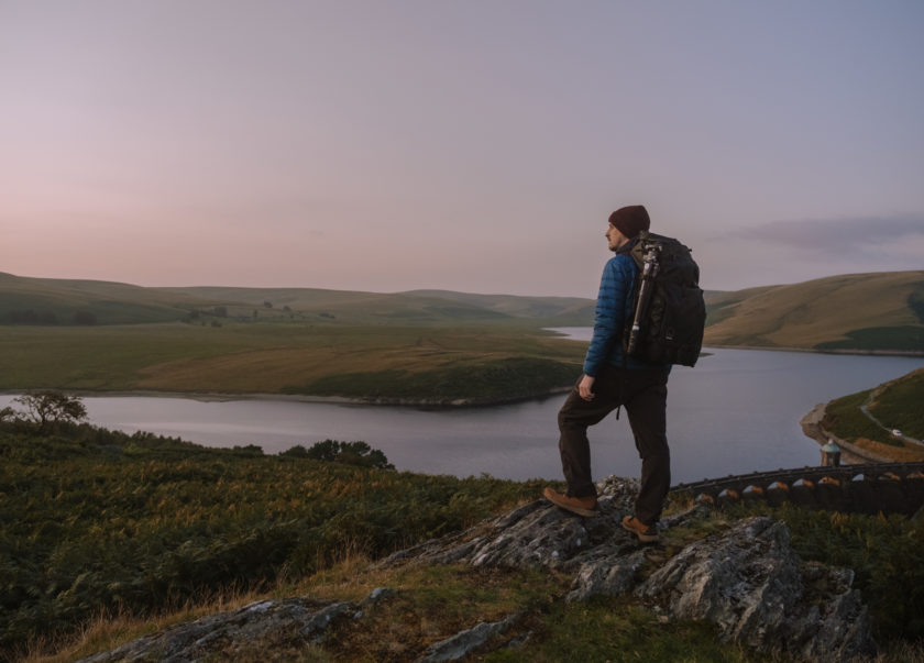 Alyn Wallace an astral photographer looking over the Elan Valley at dusk with camera in hand.